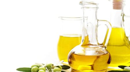 bottle of olive oil and green olives on white background