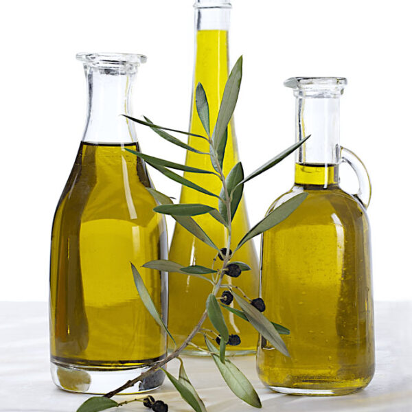 bottle of olive oil and green olives on white background